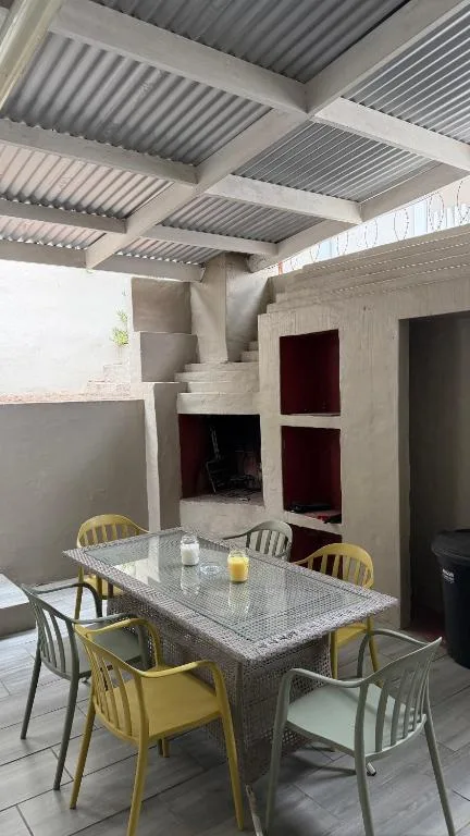Covered outdoor dining area with table and yellow chairs under metal roof