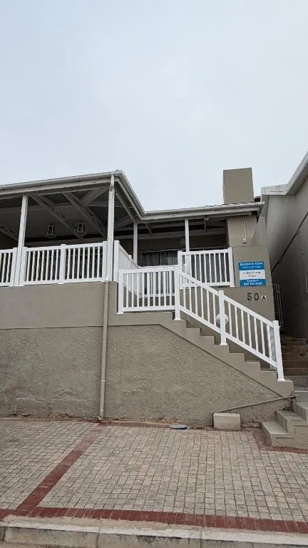 Modern self-catering home with white railings and covered deck entrance