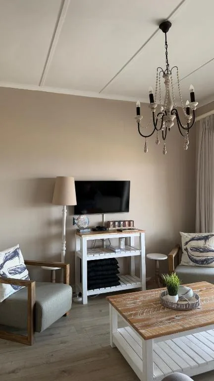 Modern living room with TV, comfortable seating, and decorative chandelier