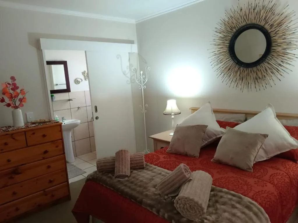 Bright bedroom with red bedding, wooden dresser, and en-suite bathroom access