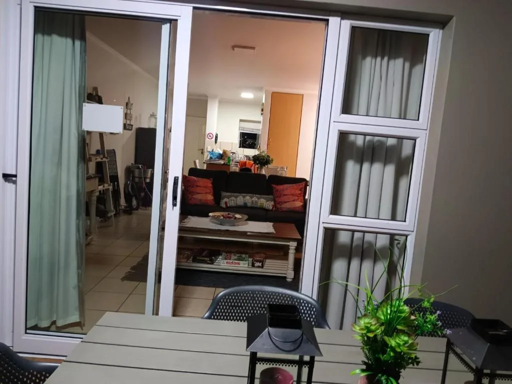 Glass doors opening onto lounge with black sofa and red cushions
