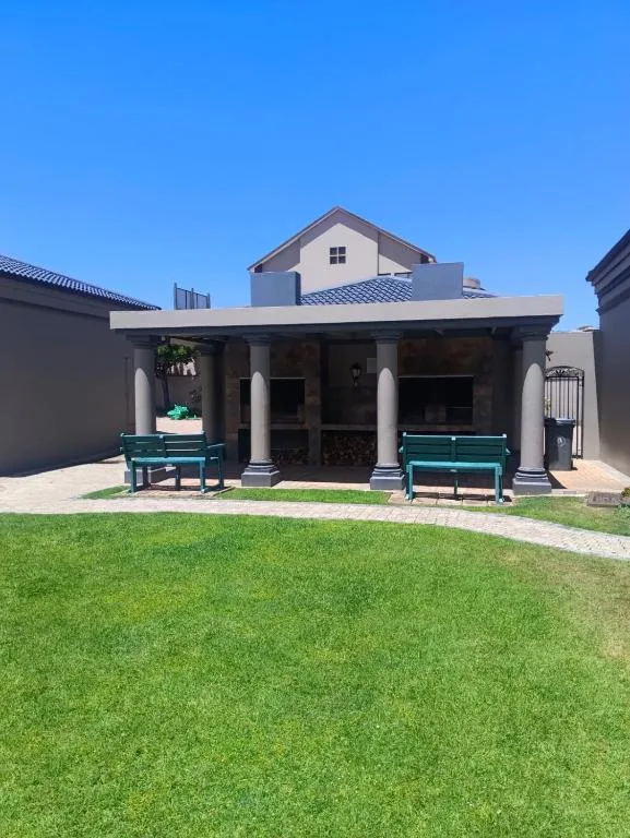 Modern home exterior with covered patio, columns, and manicured lawn