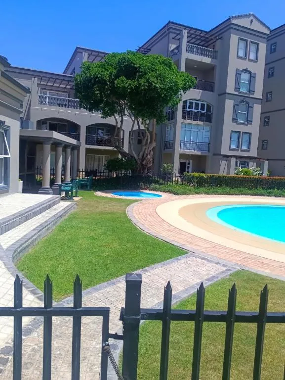 Multi-story apartment building with manicured lawn and curved swimming pool