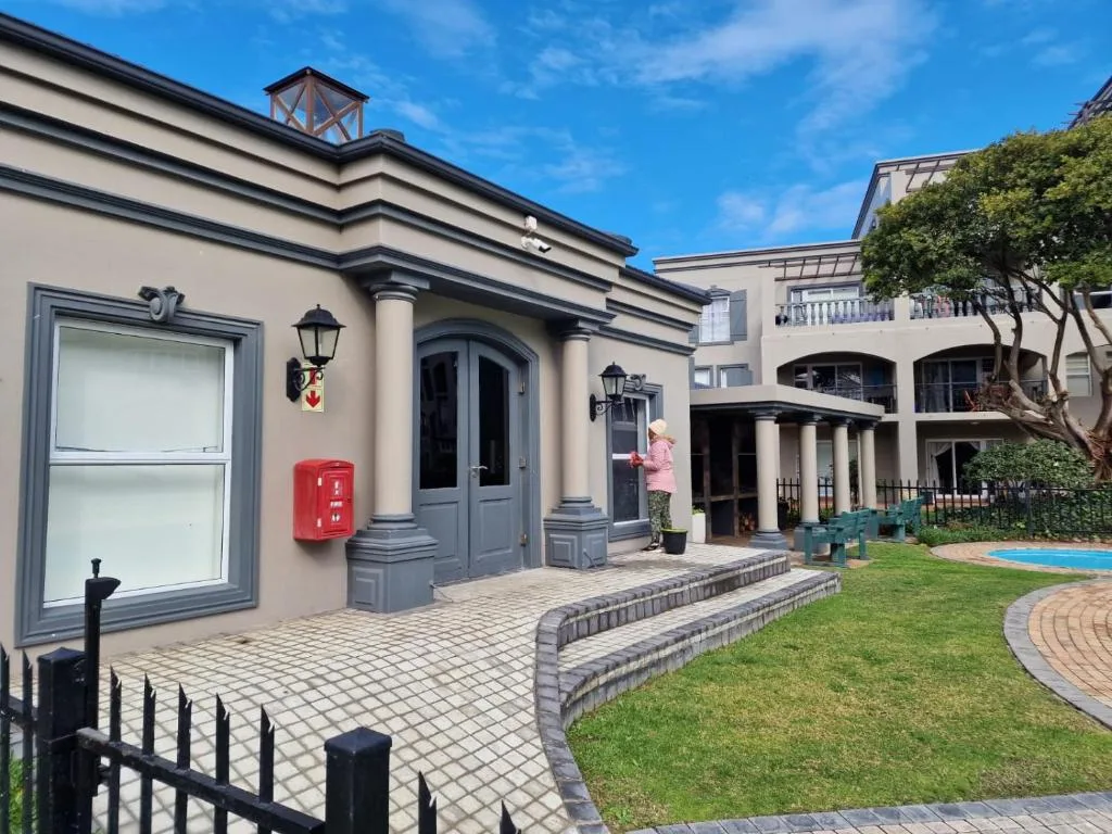 Elegant cream-colored building facade with arched entrance and manicured garden grounds