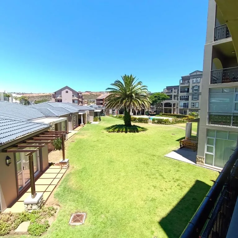 Lush green communal garden with palm tree and holiday apartments