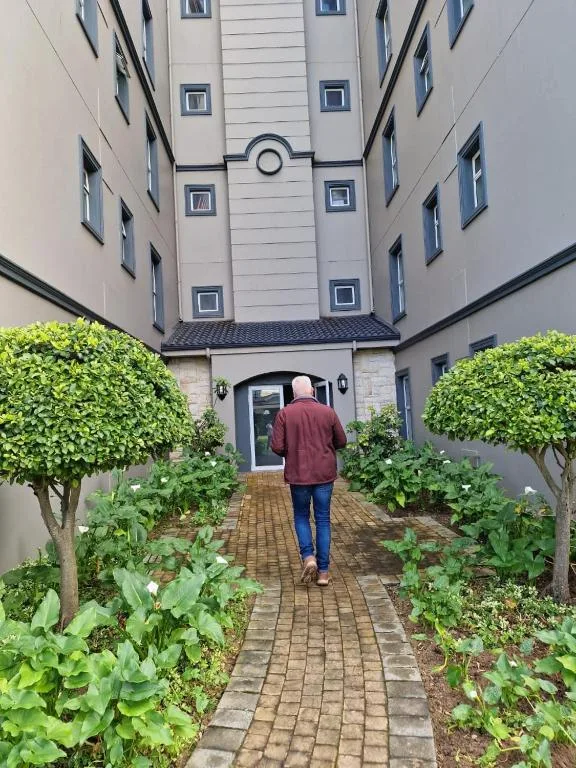 Courtyard entrance with manicured hedges and brick pathway leading to blue door