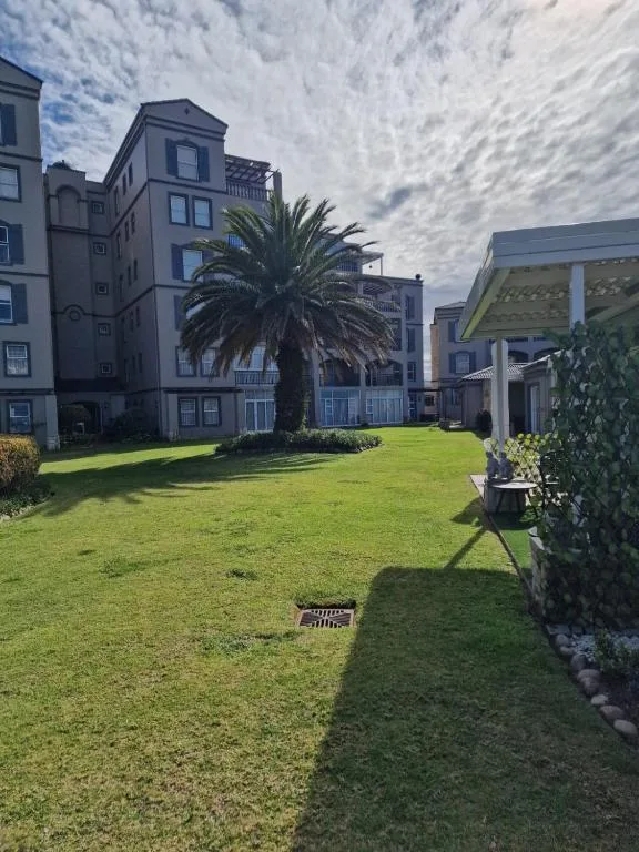Multi-story apartment building with manicured lawn and palm tree