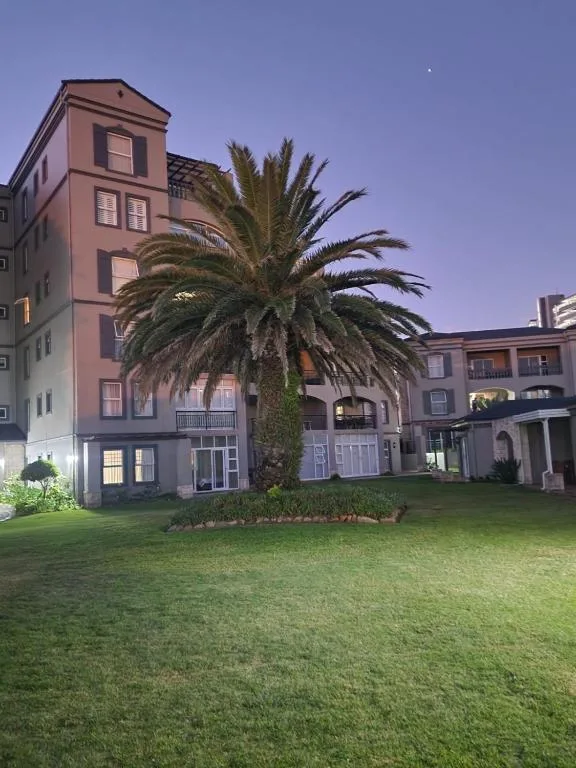 Elegant residential building facade with palm tree and manicured lawn at dusk