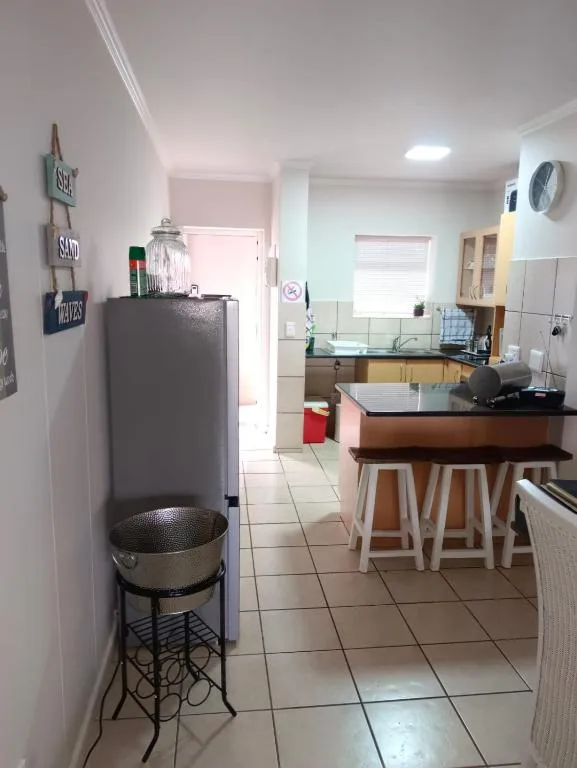 Open-plan kitchen with counter seating, appliances, and tiled flooring