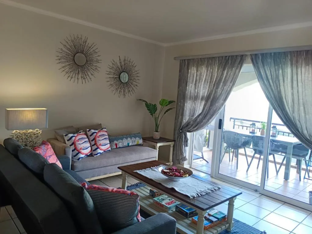 Modern lounge with gray sofas, decorative mirrors, and sea view through glass doors