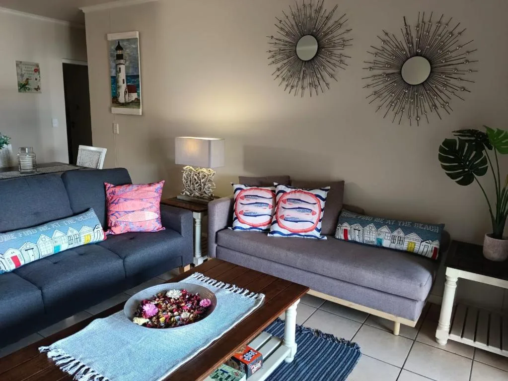 Bright living room with blue and gray sofas, decorative pillows, and modern wall mirrors