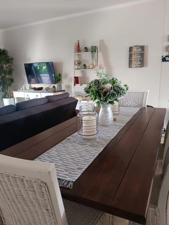 Open-plan living room with dark sofa, dining table, and wall-mounted TV display