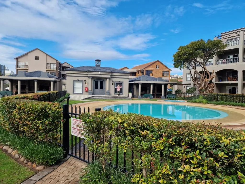 Bright blue swimming pool surrounded by manicured hedges and lawn
