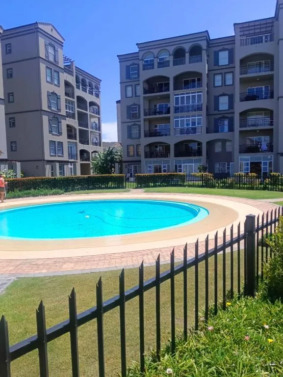 Bright blue circular swimming pool with black safety fencing and manicured lawn