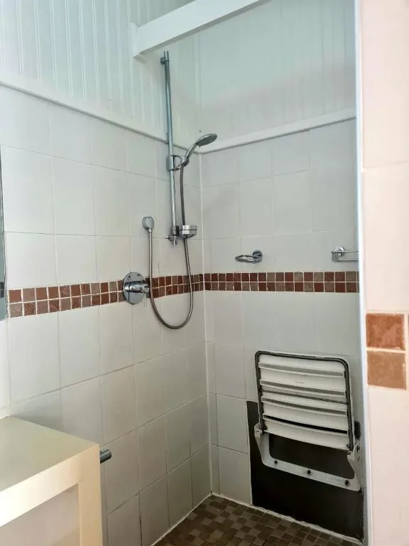 Modern shower enclosure with white tiles and terracotta accent strip