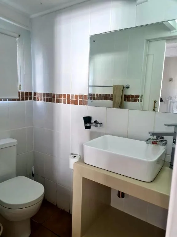 Modern bathroom with white vessel sink, mirror, and toilet fixtures