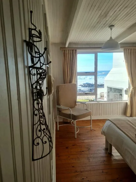 Bright bedroom with ocean view through large windows and wooden flooring