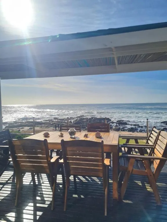 Wooden dining table with chairs on covered deck overlooking ocean