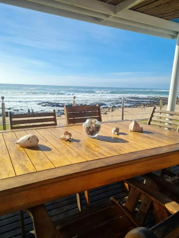 Wooden deck with ocean and beach views under covered structure