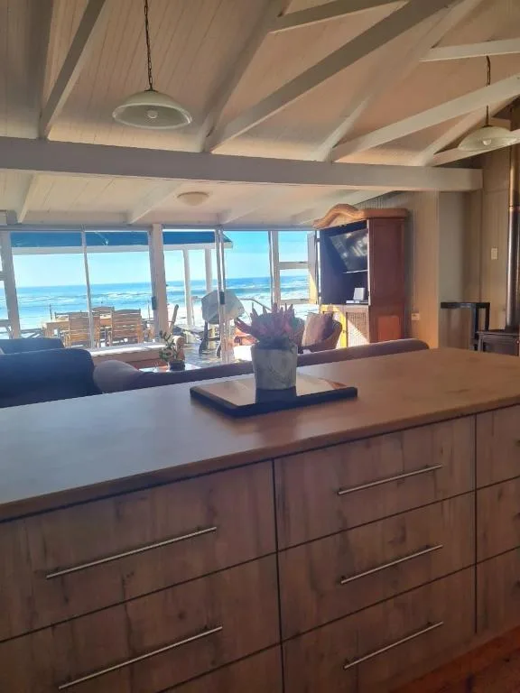 Modern kitchen with ocean view through large windows and wooden cabinetry