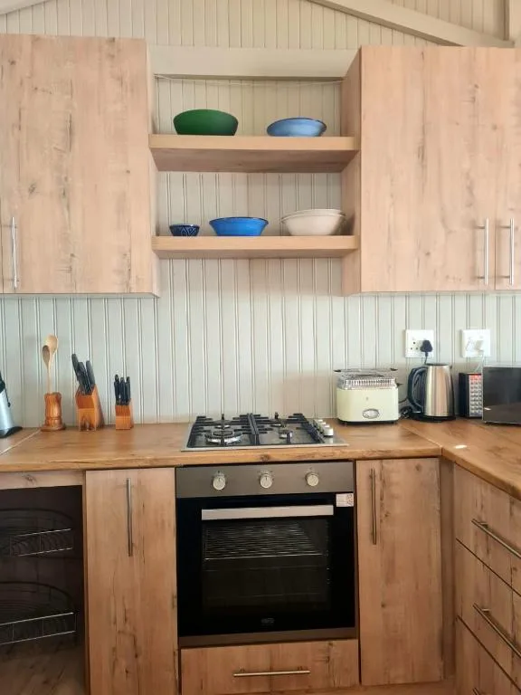Modern kitchen with gas stove, wooden cabinets, and open shelving displaying bowls