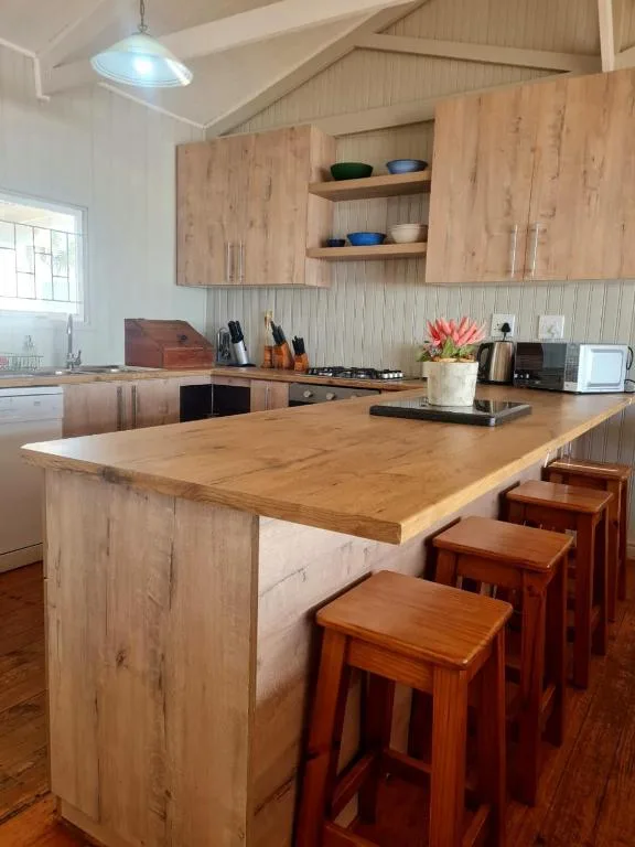 Modern kitchen with wooden cabinetry, island counter, and bar seating for guests