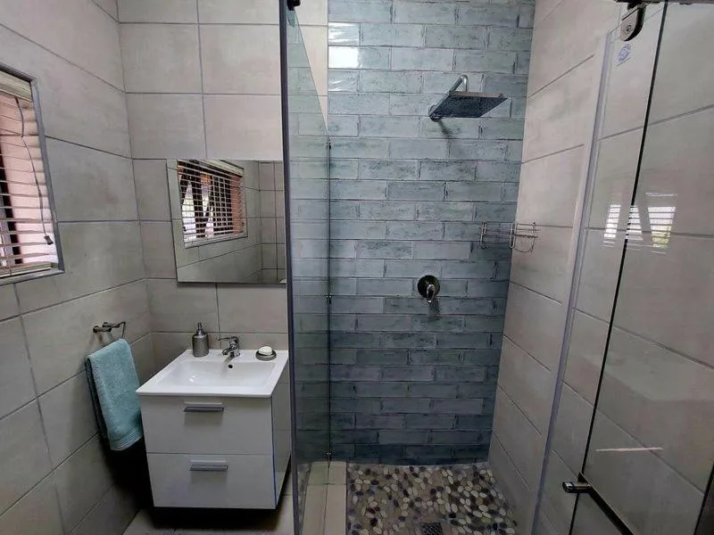 Modern bathroom with rainfall shower, vanity sink, and tiled walls
