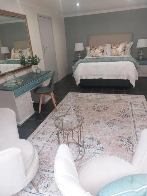 Spacious bedroom with queen bed, grey walls, vanity mirror, and elegant decor