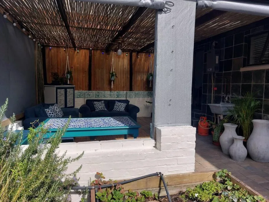 Covered patio with blue sofa, woven shade roof, and potted plants