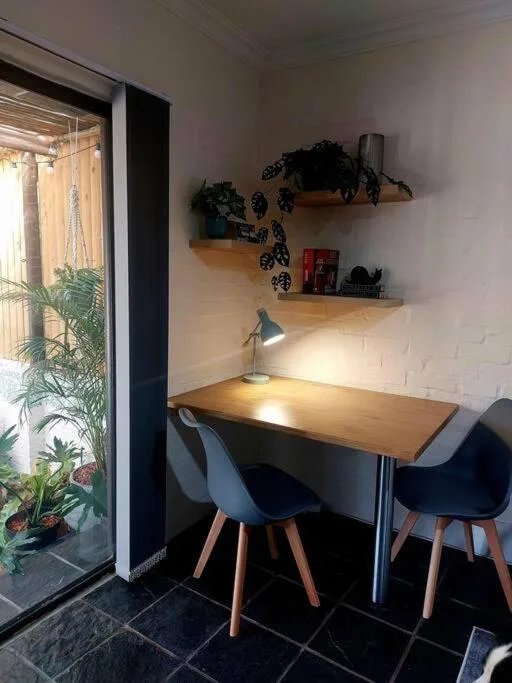 Workspace with wooden desk, modern chairs, floating shelves, and potted plants