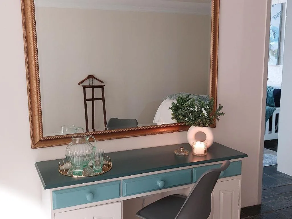 Vanity desk with mirror, decorative plant, candle, and glassware