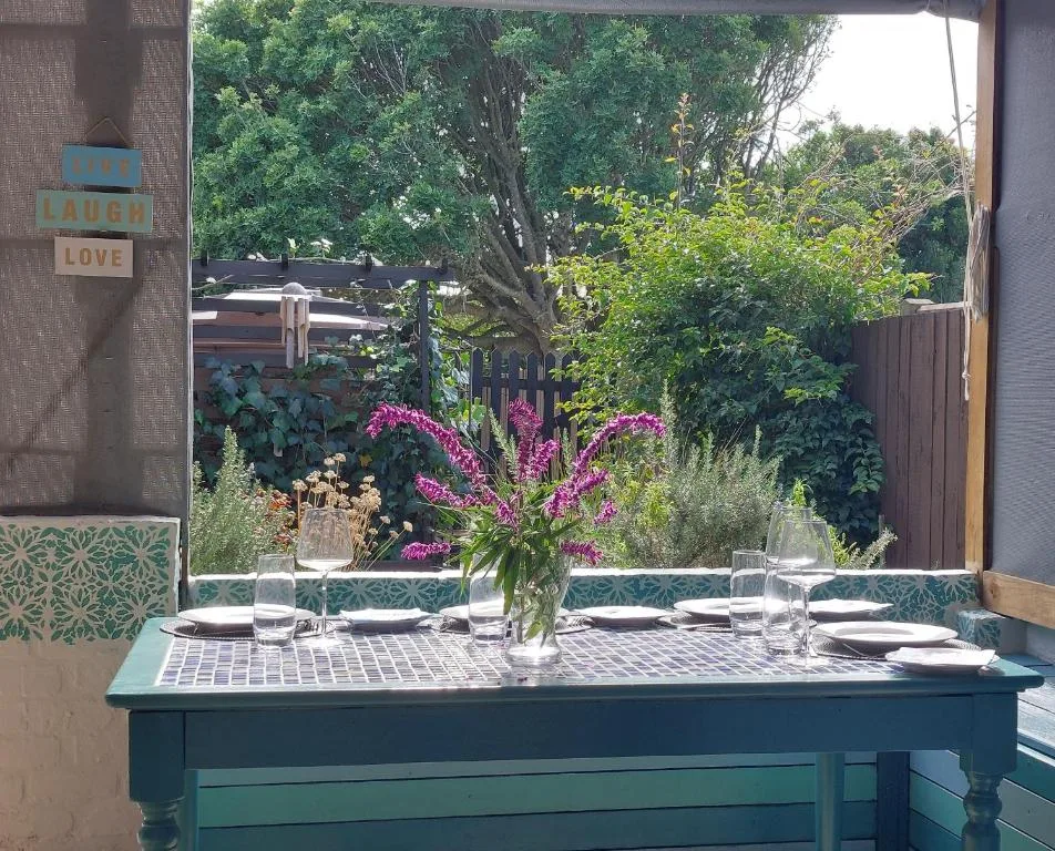 Dining table set for guests with garden views through open doors