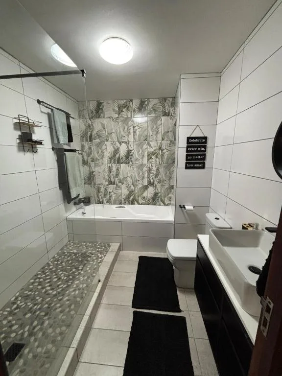 Modern bathroom with walk-in shower, white tiles, and botanical accent wall