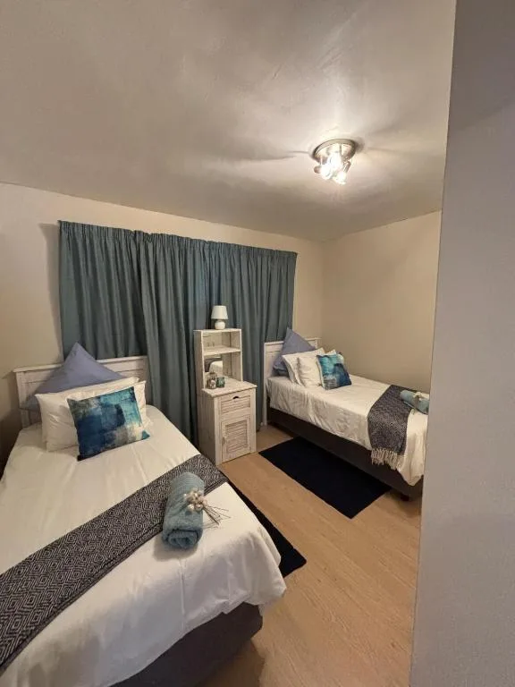 Twin bedroom with white beds, blue curtains, and coastal decor pillows