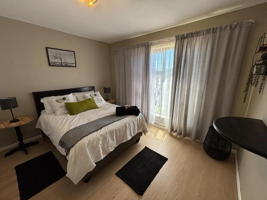 Spacious bedroom with queen bed, white linens, and large windows with sheer curtains