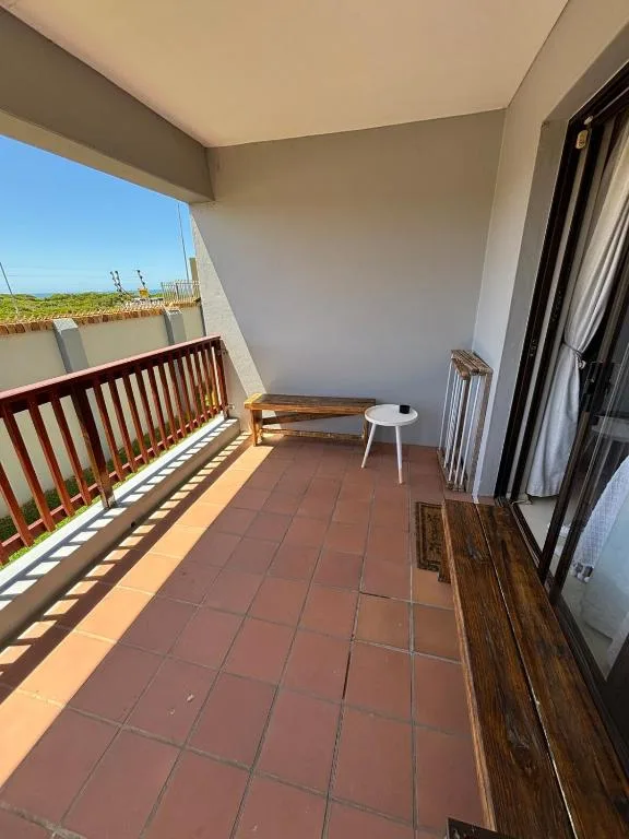 Spacious covered balcony with wooden railing and countryside view