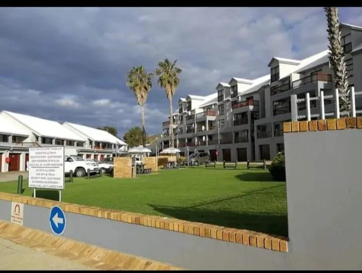 Modern apartment building complex with manicured gardens and palm trees
