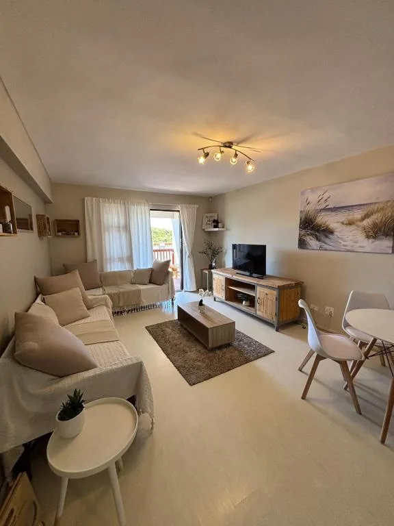 Bright living room with cream sofas, TV unit, and deck access
