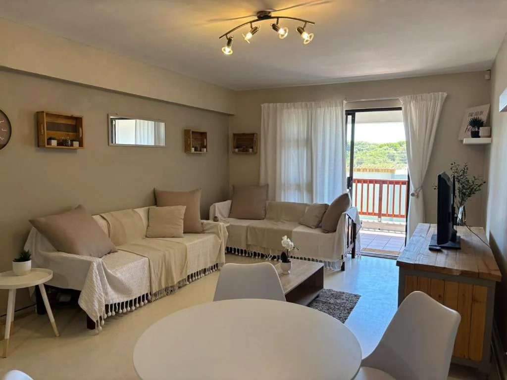 Bright lounge with cream sofa, round dining table, and deck access overlooking garden