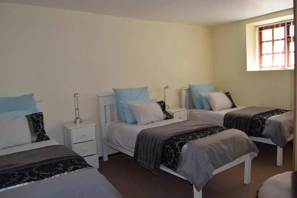 Spacious bedroom with three single beds and white nightstands