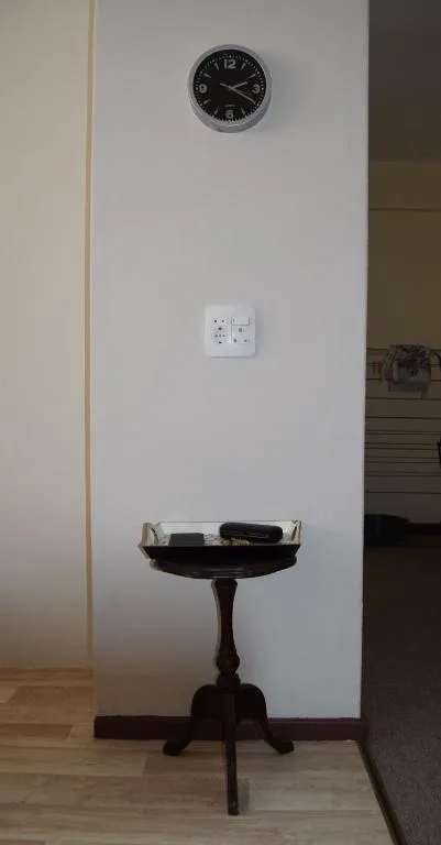 Wall clock, electrical outlet, and small wooden side table with decor