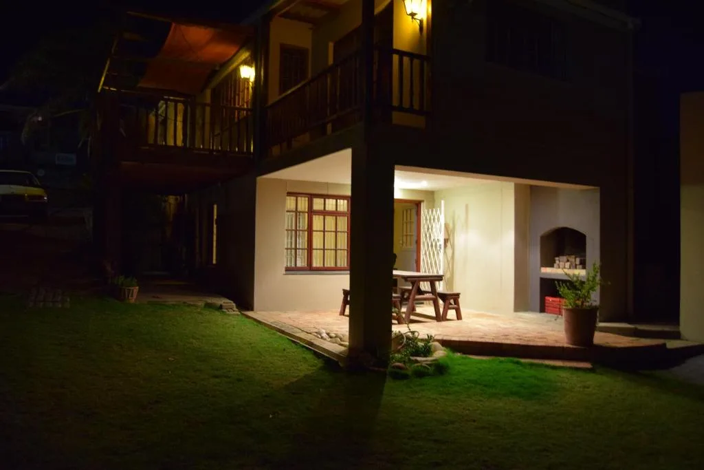 Evening view of illuminated accommodation exterior with manicured lawn and patio