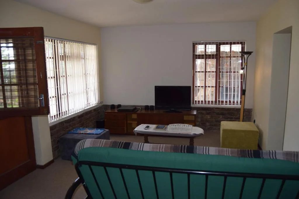 Spacious living room with TV, striped sofa, and natural light from windows