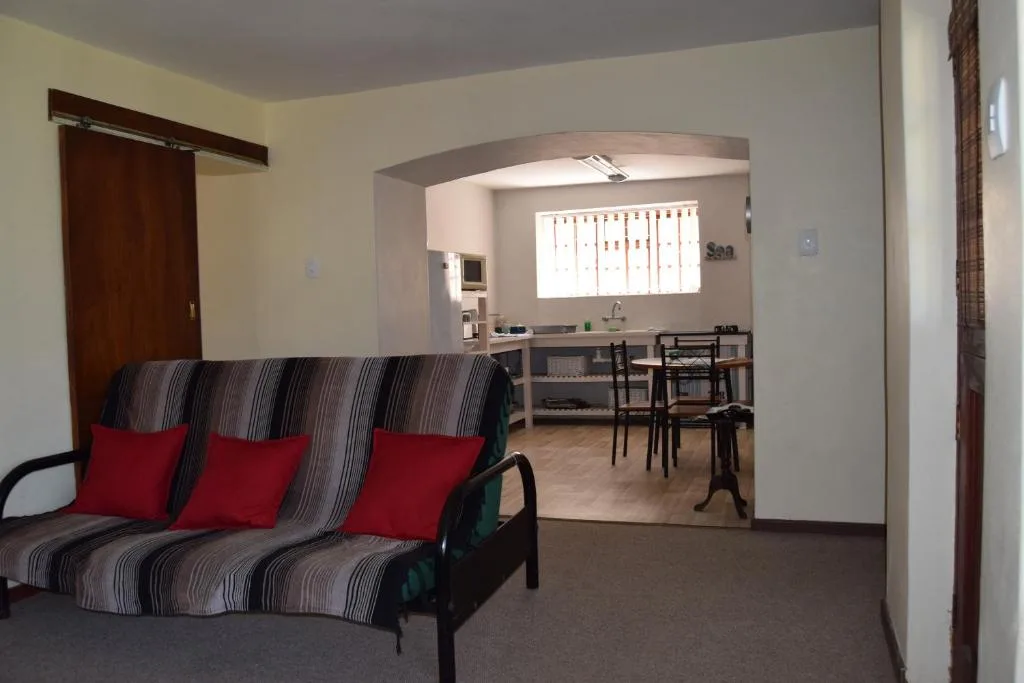 Open-plan lounge with striped sofa and red cushions, kitchen visible beyond