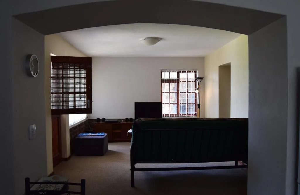 Open-plan lounge area with sofa, TV, and natural light from windows