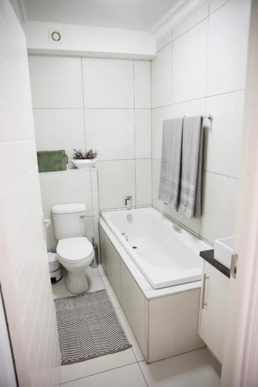 Clean white bathroom with toilet, bathtub, and towel rack
