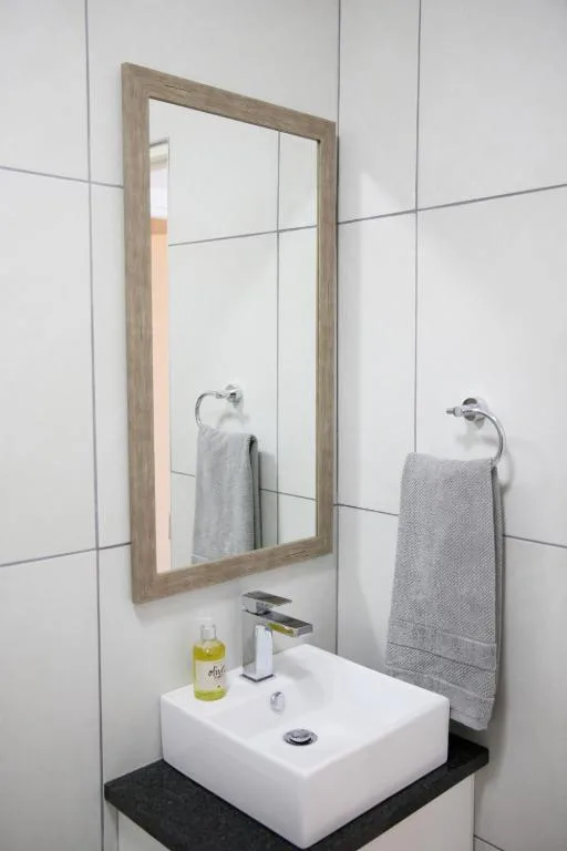 Modern bathroom vanity with white rectangular sink and wooden-framed mirror