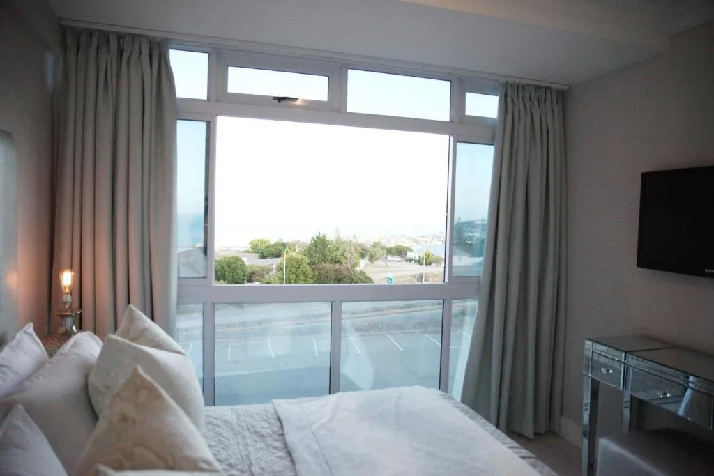 Bright bedroom with large windows overlooking Mossel Bay and coastal landscape views