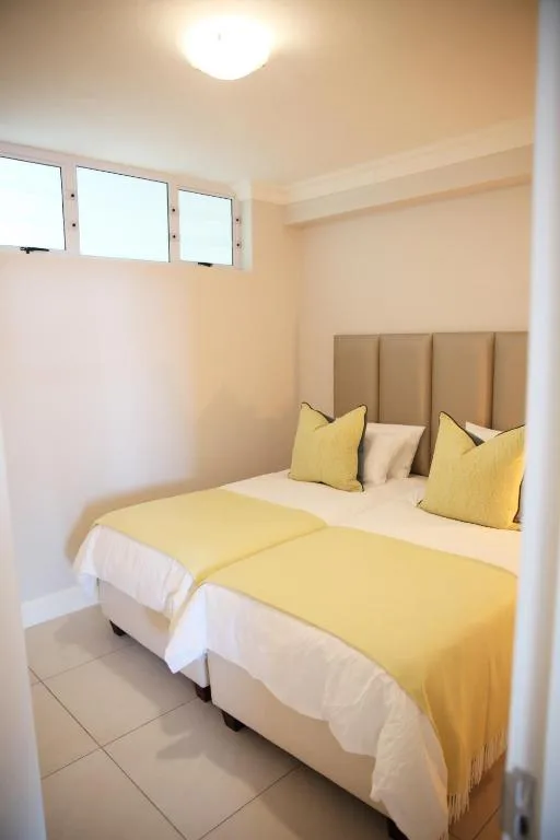 Bright bedroom with twin beds, yellow bedding, and upholstered headboard