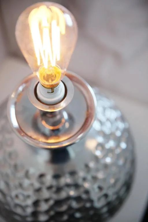 Glowing vintage Edison bulb in decorative textured lamp fixture